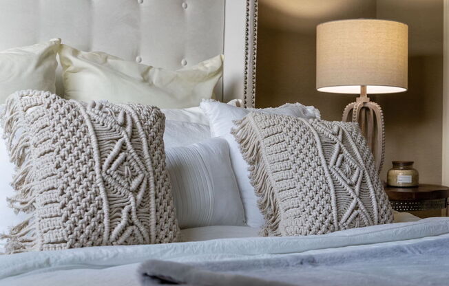 a bed with knit pillows and a plush headboard