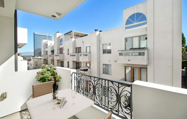 a balcony with a table and chairs and a building in the background