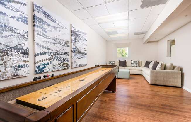 a game room with a shuffleboard table and couches