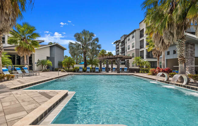 a swimming pool with palm trees in front of an apartment building