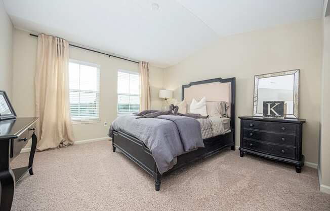 A bedroom with a large bed and a dresser with a mirror.