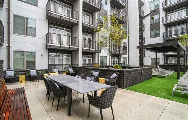 an outdoor patio with a table and chairs in front of an apartment building at Link Apartments® Mint Street, Charlotte, NC, 28203