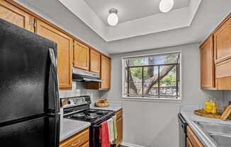 a kitchen with black appliances and wooden cabinets and a window