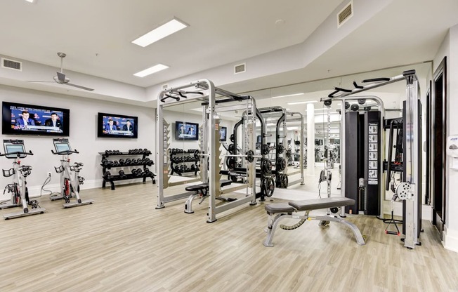 a gym with weights machines and televisions on the wall