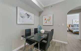 a dining area with a glass table and four black chairs