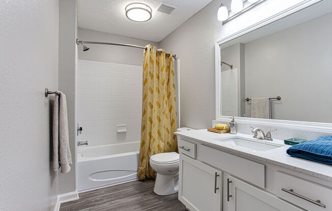 a white bathroom with a yellow shower curtain