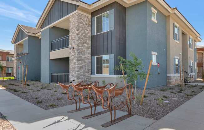A modern house with a grey and brown exterior and a sculpture of horses in front.