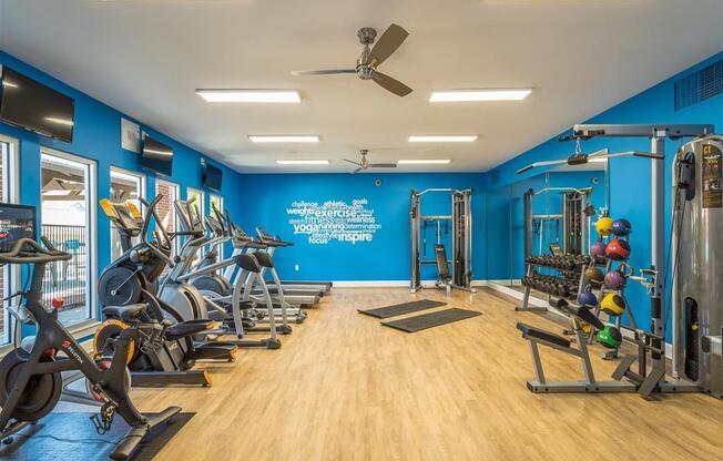 a gym with exercise equipment and a ceiling fan