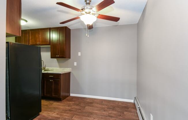 an empty kitchen with a ceiling fan and a refrigerator. Roseville, MN Rosedale Estates