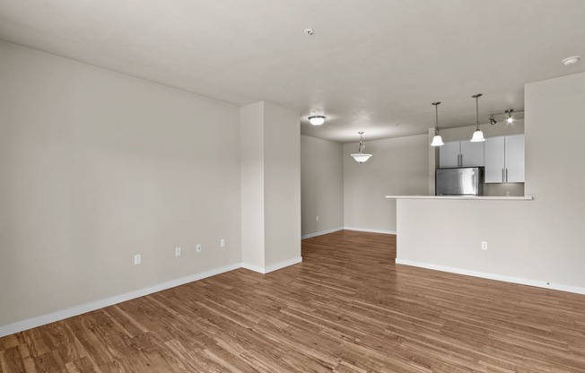 an empty living room with a kitchen in the background