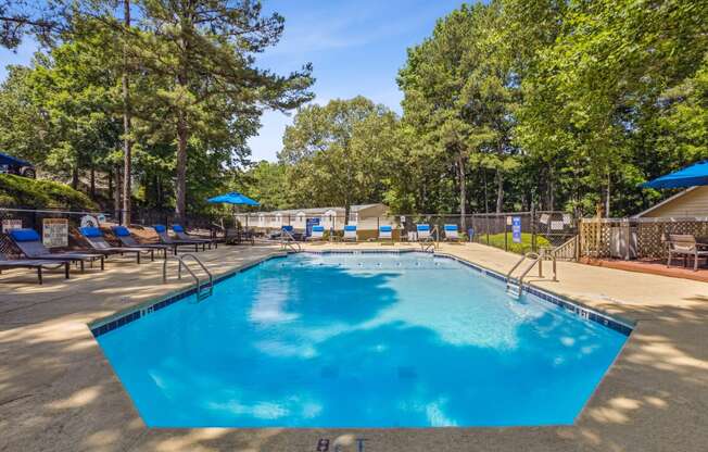 our resort style swimming pool is surrounded by chairs and trees