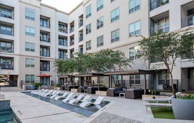 A modern apartment complex with a pool and outdoor seating area.