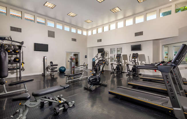A gym with a variety of equipment including treadmills, weights, and exercise machines.