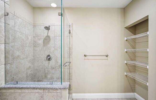 A walk-in shower with a glass door and a bench seat.