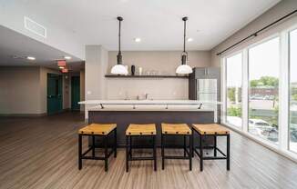 A modern kitchen with a bar area and three stools.
