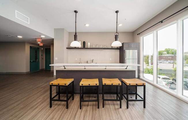 A modern kitchen with a bar area and three stools.