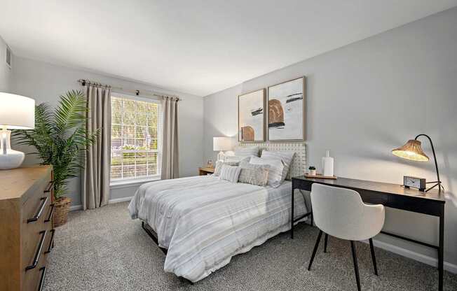 A bedroom with a bed, desk, chair, and window.