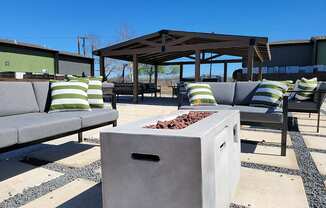 a fire pit on a patio with chairs and a gazebo at Ivy Plains at Brooks Apartments, San Antonio , 78223