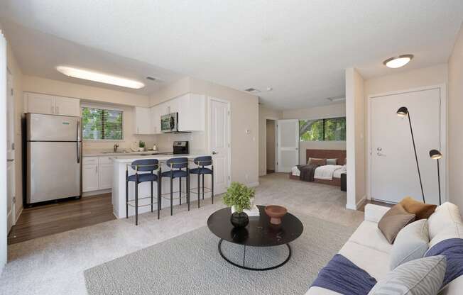 a living room with a couch and a table in front of a kitchen