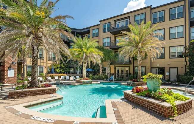 A pool surrounded by palm trees and a brick wall.