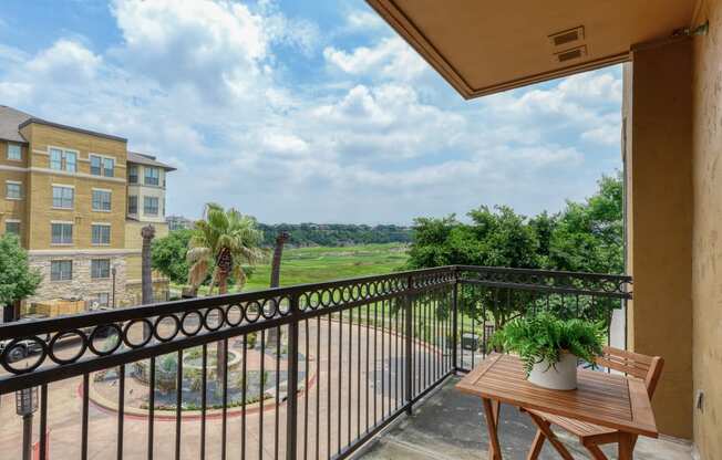 a balcony with a table and chairs and a view of a garden