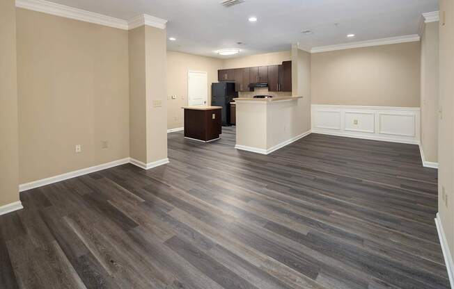 A spacious room with wooden flooring and a kitchen area.