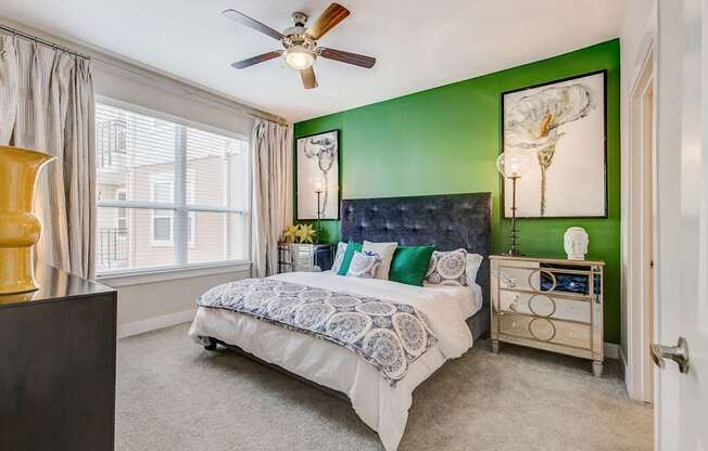 A bedroom with a bed, dresser, and ceiling fan.