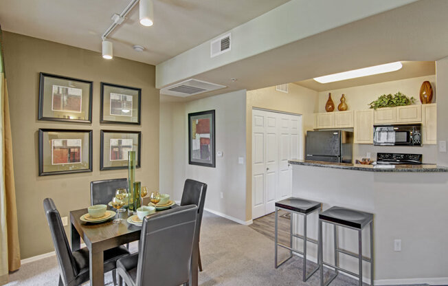 a dining area with a table and chairs and a kitchen in the background