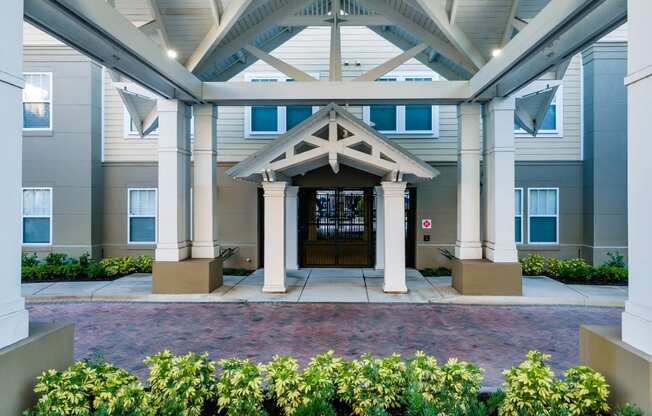 the front entrance of an apartment building with columns and a door