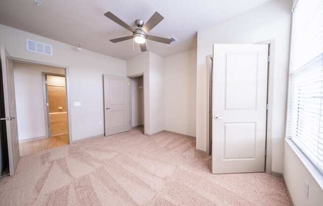 an empty living room with a ceiling fan and a closet