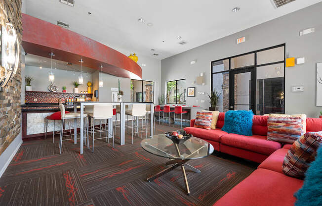 A living room with a red couch and a glass coffee table.