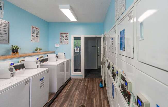 a laundry room with many washes and dryers and a door to a hallway