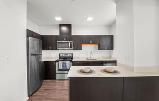 a kitchen with dark cabinets and white countertops