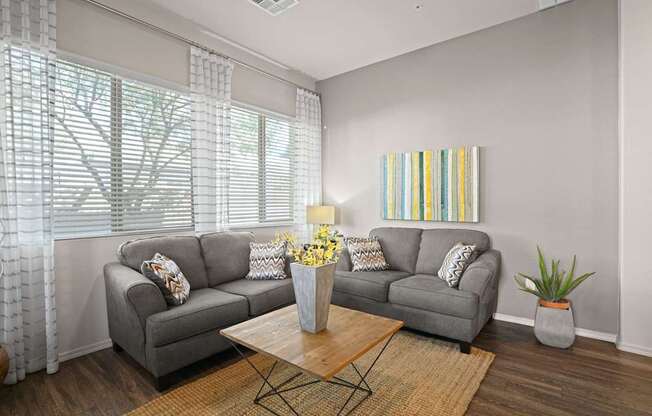 A living room with a grey couch, a coffee table, and a painting on the wall.