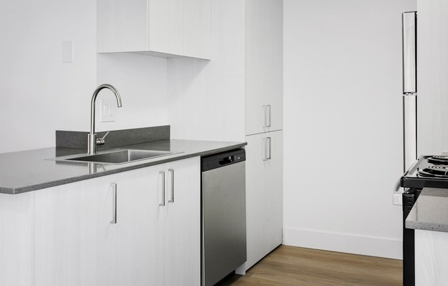 A modern kitchen with white cabinets and a stainless steel sink and dishwasher.