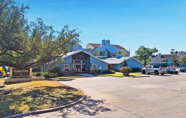 A parking lot with cars and a building with a sign that says Nicholas Park.