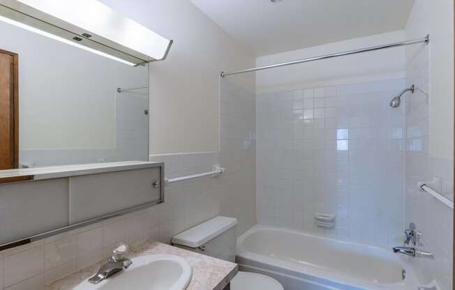 a bathroom with a tub and a sink and a mirror. Fargo, ND Windsor Apartments