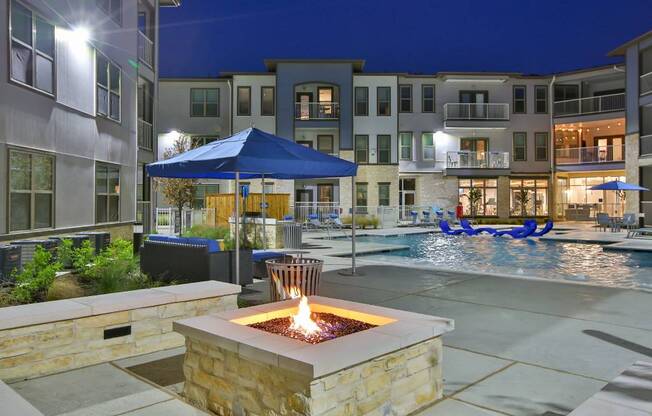 an outdoor area with a fire pit and a pool at night