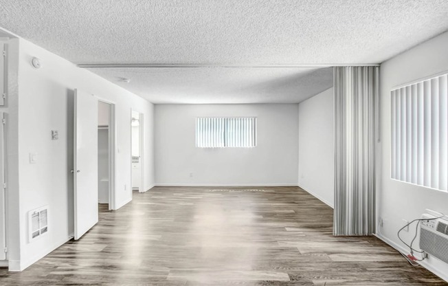 an empty living room with white walls and a wood floor