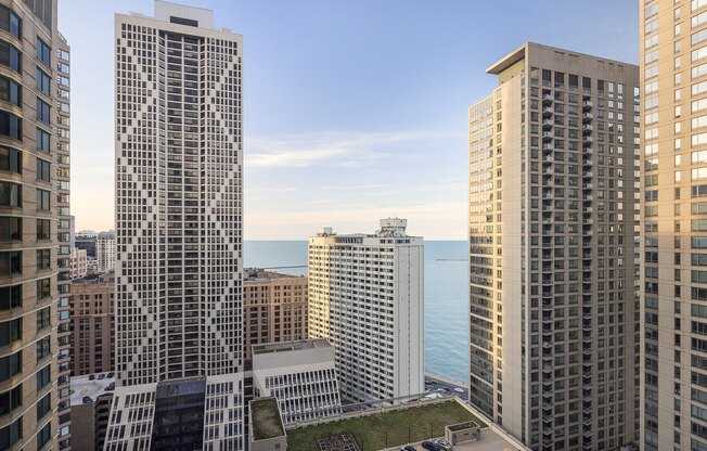 A cityscape with a large building in the middle and a body of water in the background.