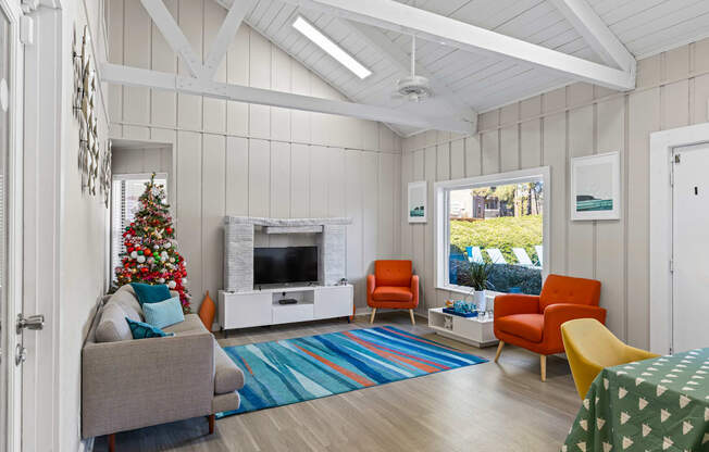 A living room with a grey couch, a Christmas tree, and a fireplace.