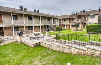 the backyard of an apartment building with a fire pit