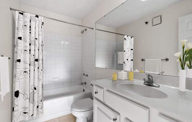 A white bathroom with a toilet, sink, and shower.