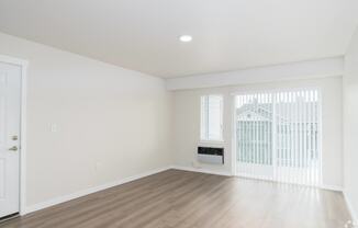 an empty living room with white walls and a window with a radiator and a door