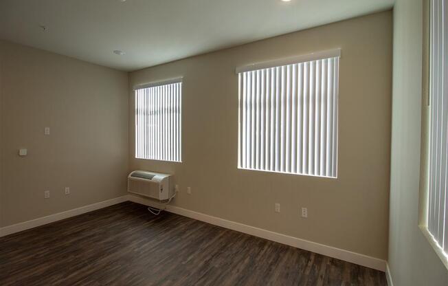 an empty room with two windows and a air conditioner at Loma Villas Apartments, California, 92408