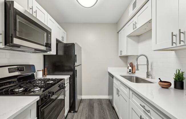 an empty kitchen with white cabinets and stainless steel appliances