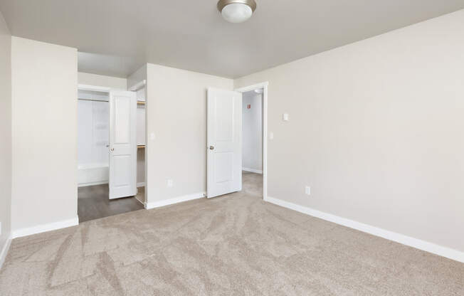 A room with a carpeted floor and two doors.