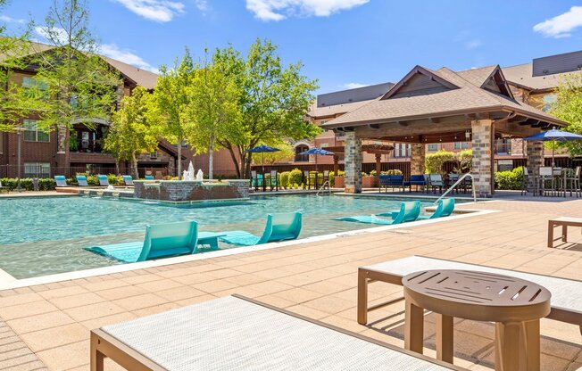 a swimming pool with lounge chairs and a table