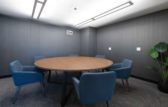 a small meeting room with a round table and blue chairs