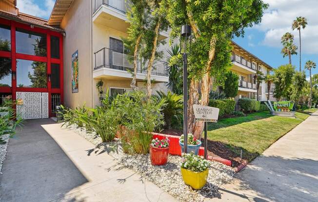 a sidewalk in front of a building with plants and trees